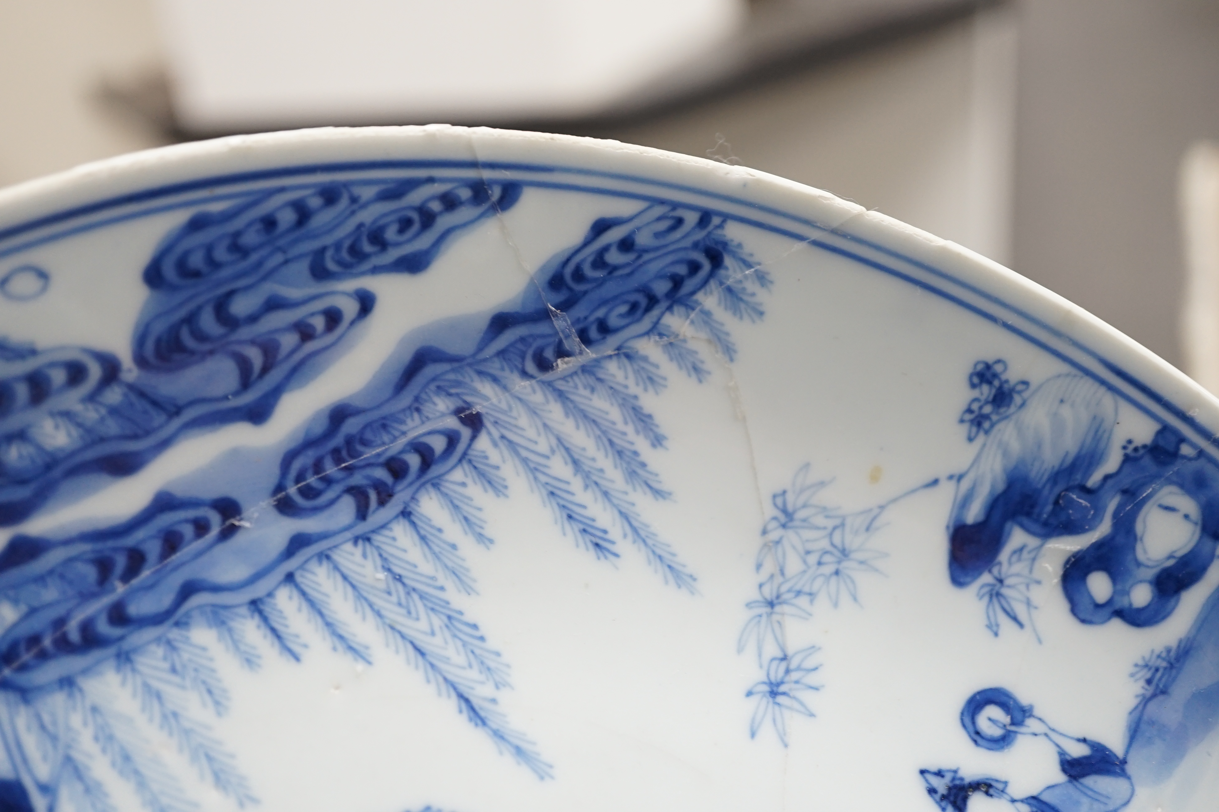A Chinese blue and white dish, Kangxi period, broken and messily reglued